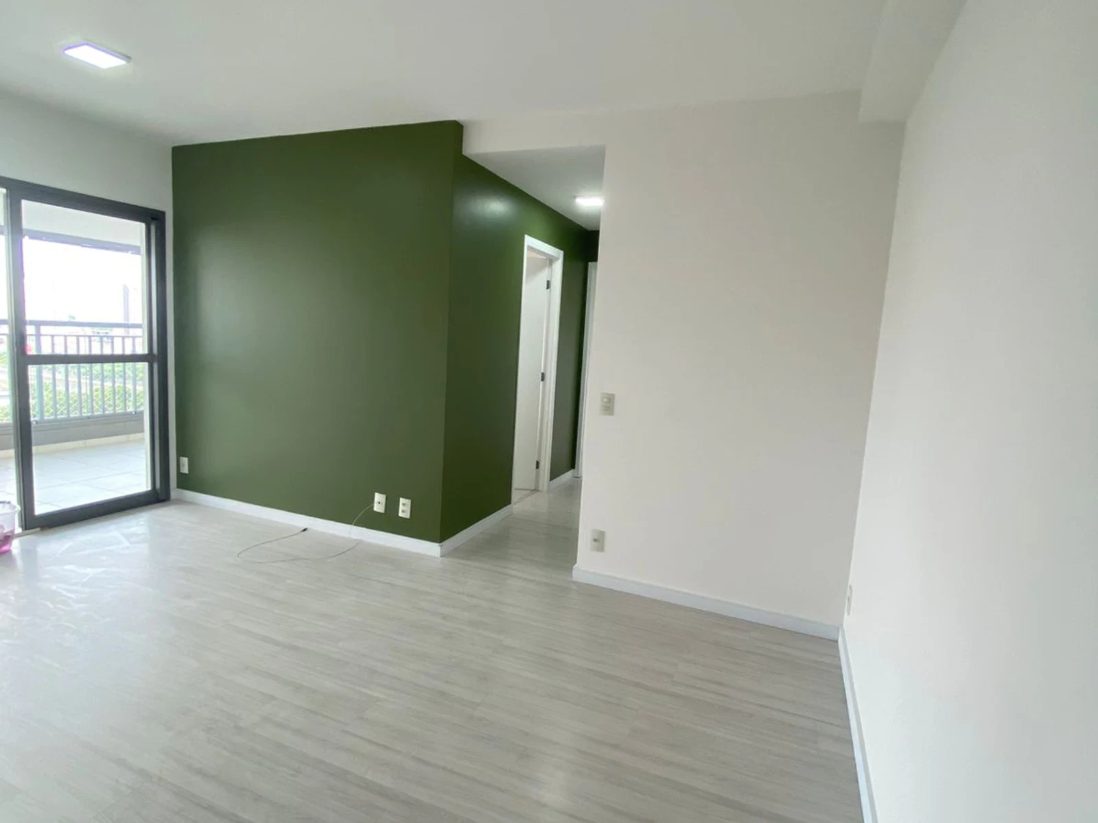Sala finalizada no Tatuapé com parede verde e acabamento branco